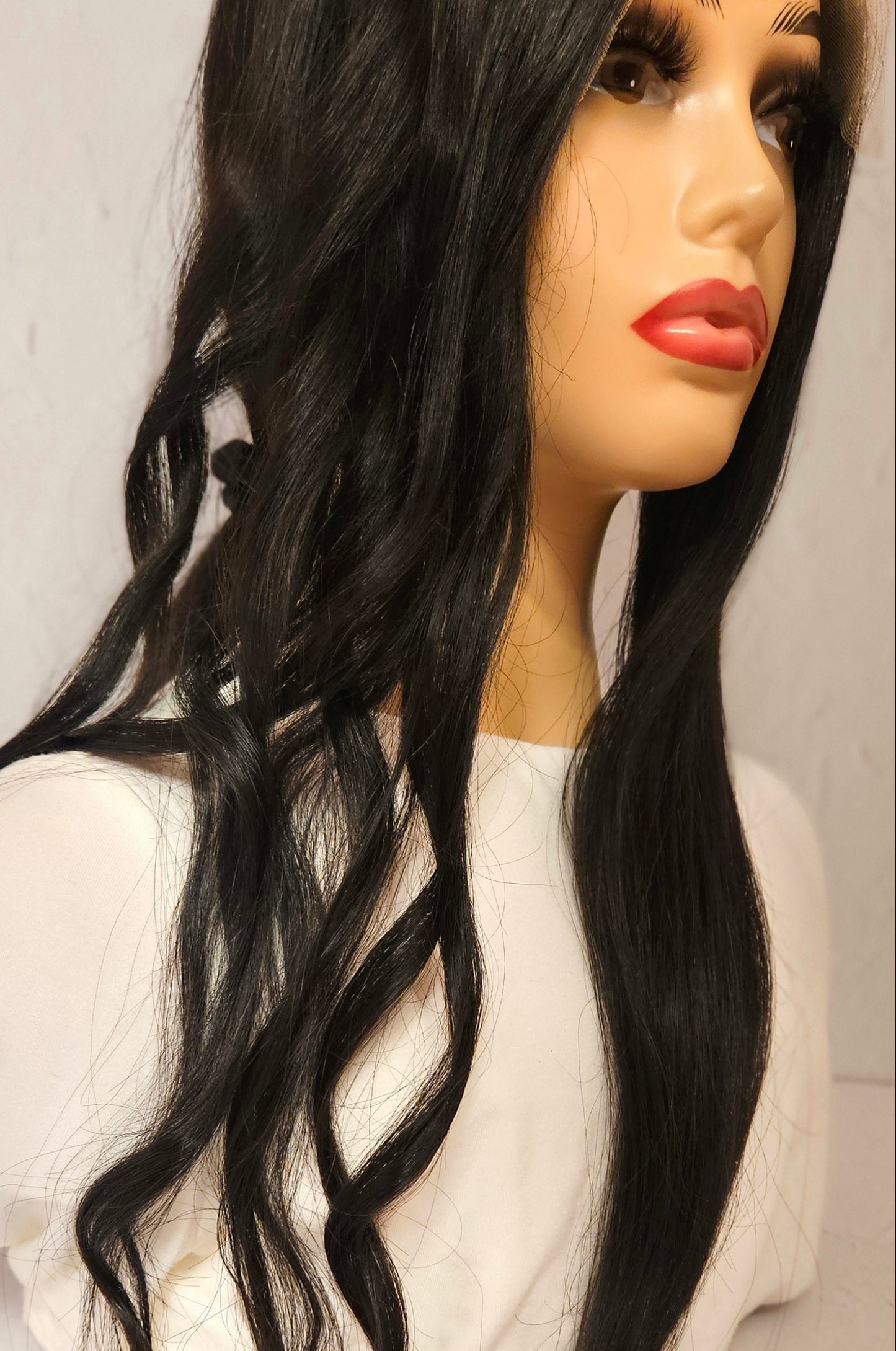 Mannequin head with long black hair on a plain background